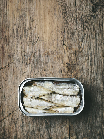 open sardines can on old wooden kitchen table, top view