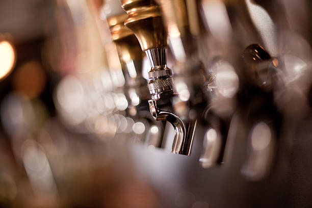 Image focusing on the taps in a brewery Soft focus on a line of beer taps with only one in focus. beer pump stock pictures, royalty-free photos & images