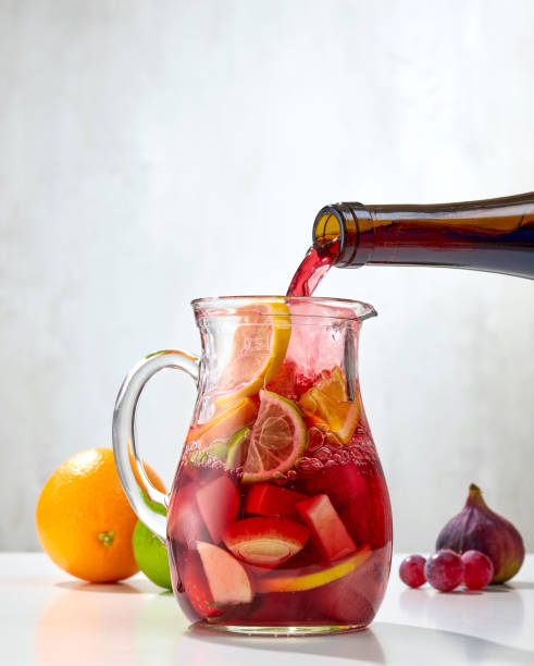 red wine pouring into jug of cutted fruits red wine pouring into jug of cutted fruits. process of making red sangria sangria stock pictures, royalty-free photos & images