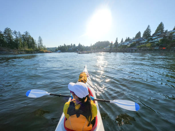 młoda eurazjatycka kobieta ciesząca się widokiem podczas spływu kajakowego wzdłuż wybrzeża mieszkalnego - district of north vancouver zdjęcia i obrazy z banku zdjęć