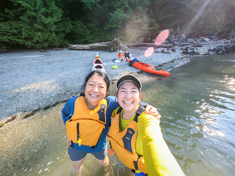Madre asiática e hija euroasiática Kayakistas tomando selfie en la playa photo