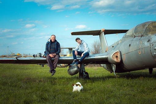 Son with father in front of an old abandoned Soviet aircraft. The guy likes to study old technology. Dad is a photographer.