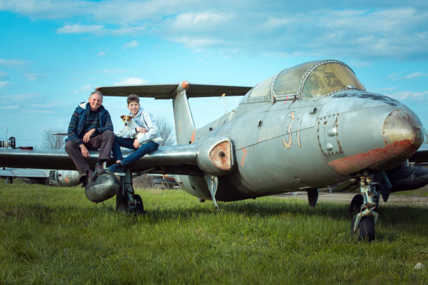 Son with father in front of an old abandoned Soviet aircraft. The guy likes to study old technology. Dad is a photographer.