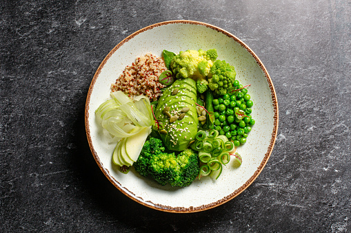 Green vegan bowl with avocado, quinoa, green peas, broccoli and cucumber. Above.