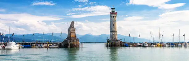 Lake Constance, panoramic view of harbor entrance in Lindau island, Germany, Europe. Landscape with old lighthouse in marina, scenic panorama of Bodensee in summer. Lindau is attraction of Bavaria.