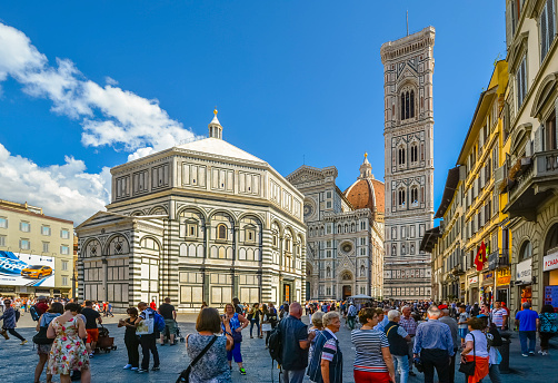 Tourists crowd the Piazza Duomo near the Baptistery, Cathedral and Tower in the historic center of the Tuscan city of Florence, Italy.
