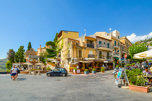 Sunny, summertime view of a picturesque street of cafes and shops near the main street Corso Umberto in the colorful Italian village of Taormina, Italy, on the island of Sicily.
