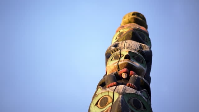Close up shot of a totem pole against a blue sky