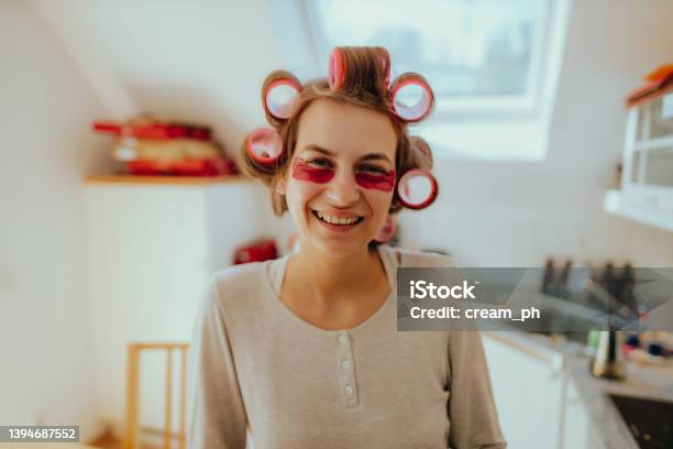 Smiling Woman Using Hair Rollers And An Eye Mask At Home Stock Photo - Download Image Now
