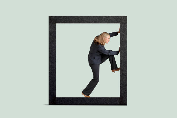 Woman Boxed In A businesswoman attempts to free herself from the parameters established around her as she lifts her leg to help push against the boundaries. stuck stock pictures, royalty-free photos & images