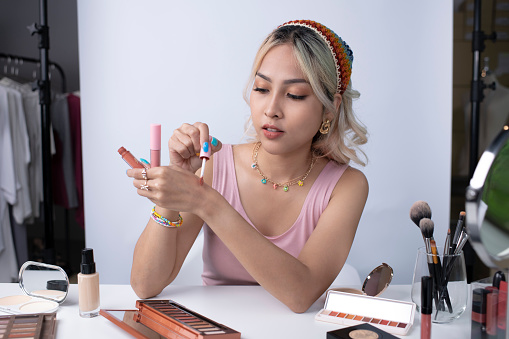 Young beautiful Asian woman and professional beauty make up artist vlogger or blogger recording makeup tutorial to share on website or social media. Business online influencer on social media concept.