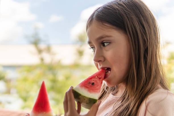 아이는 잘 익은 붉은 육즙이 많은 수박 조각을 물립니다. 여름에 수박을 먹는 귀여운 소녀 - watermelon missing bite melon grass 뉴스 사진 이미지