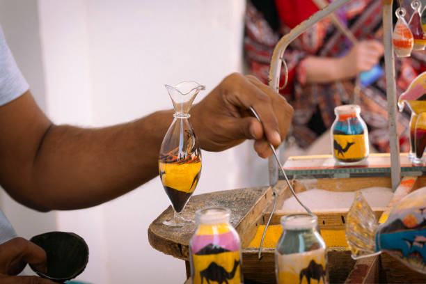 Making multicolored sand for handmade souvenirs. man pours multicolored sand into a glass jug