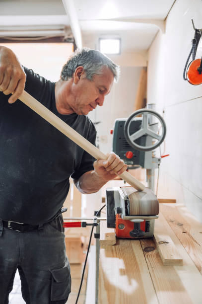 istock Carpenter sanding down the edges on a wooden stick 1394711115