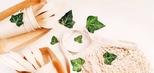 Fabric bag for food delivery.Disposable eco cutlery,plates,spoons,knives,forks on a light background.Copy space.Paper cups,fast food containers.Recycling,eco-friendly concept.Eco craft paper tableware vajilla de papel eco artesanal. vasos de papel, recipientes de comida rápida. espacio de copia. reciclaje, concepto ecológico. cubiertos ecológicos desechables, platos, cucharas, cuchillos, tenedores sobre un fondo claro. bolsa de tela para entrega de a
