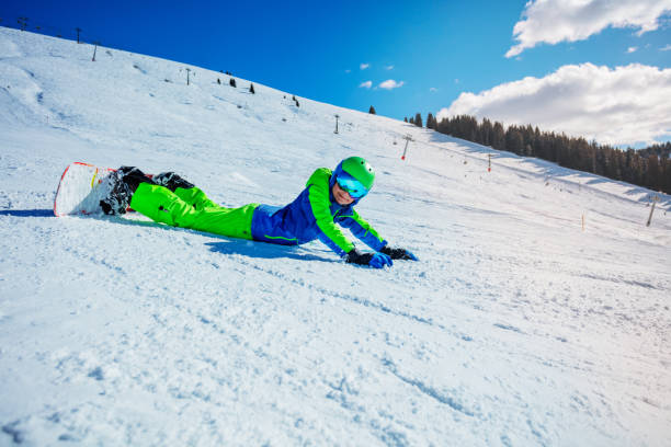 istock Boy with snowboard lay on the ski slope 1394711700