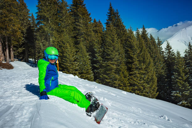 istock Snowboarder child sit in snow at winter mountain forest 1394711729