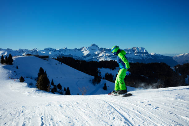 istock Boy going down ski slope on snowboard from the mountain 1394711733