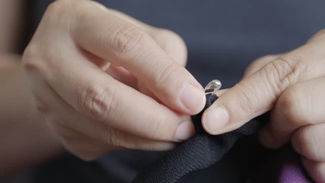 Woman hands put safety needle pin on the cloth.