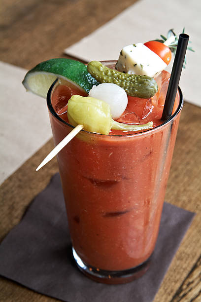 A Bloody Mary is garnished with cheese, vegetables, and lime stock photo