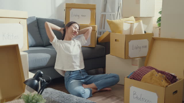 Asian lady sit on floor feel happy and relax moving home finish.