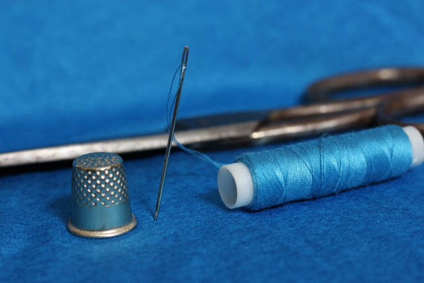 istock Spool of Blue Thread, Thimble and Needle on Blue Fabric 1394718399