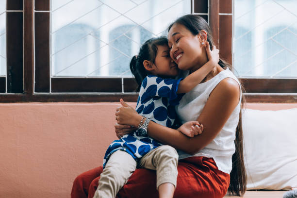 A smiling Asian mother and her little daughter hugging.