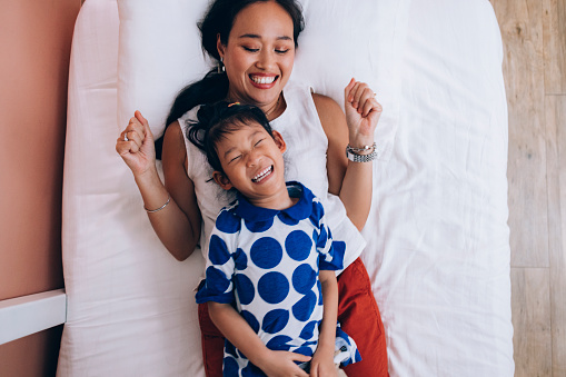 An overhead shot of happy mother and her little girl hugging on the bed.