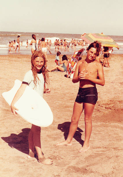 Boy and girl on vacation at the beach Analog image of a girl and a teenage boy at the beach. Vintage image from the eighties. nostalgia 80s stock pictures, royalty-free photos & images