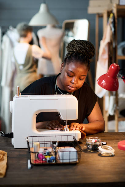 istock Young contemporary seamstress with electric sewing machine creating new clothes 1394722710
