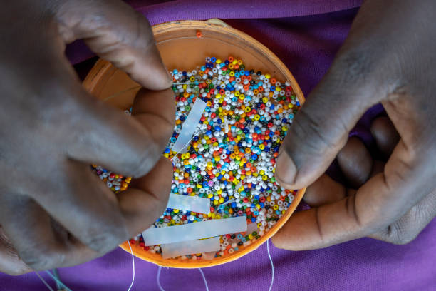 Making of handmade jewellery. Box with beads and african women hands, top view, close up. Island of Zanzibar, Tanzania, Africa stock photo