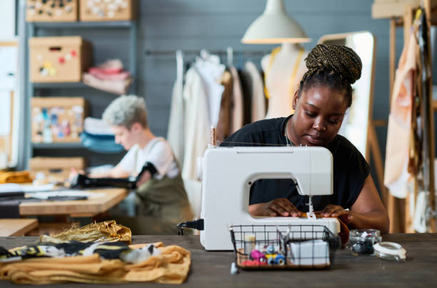 istock Young African American businesswoman using electric sewing machine at work 1394722978