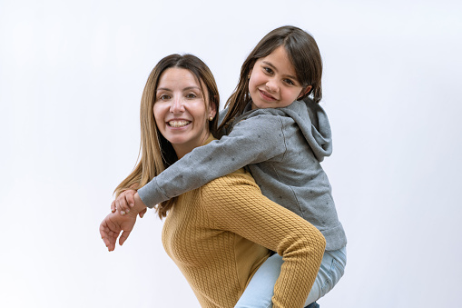Latin mother and daughter together by a white background