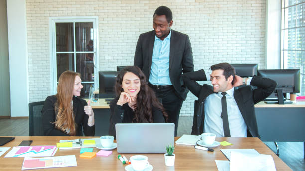 istock Full concentration at work. Group of young business people working and communicating while sitting at the office desk together with colleagues sitting in the background 1394724695