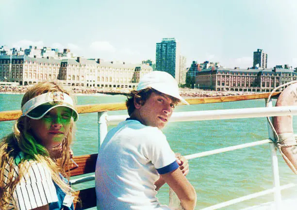 Analog photo of a teenage boy and a girl on a boat trip during summer vacation from the eighties. Grainy image from the eighties.