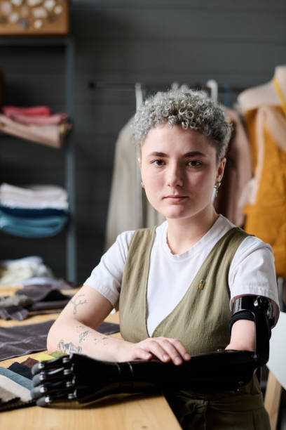 istock Young serious female tailor or clothes designer sitting by workplace in studio 1394725532