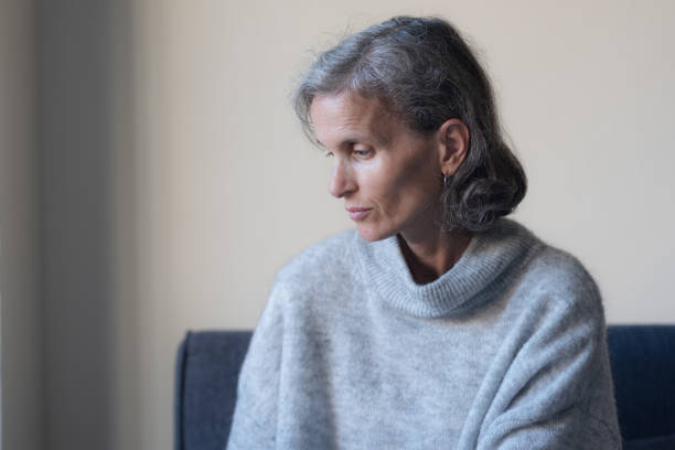 istock Seated middle aged woman in grey sweater looking down 1394726361