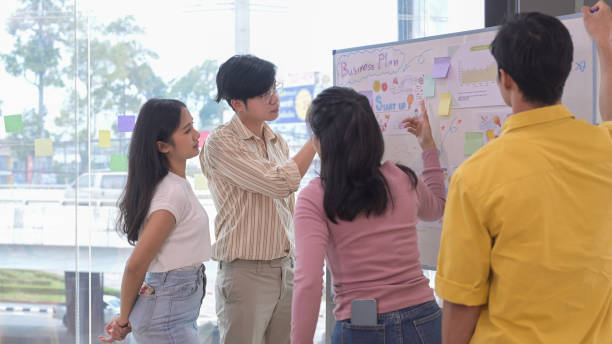 istock Focused start up business team working together and writing ideas on whiteboard during meeting. 1394728100