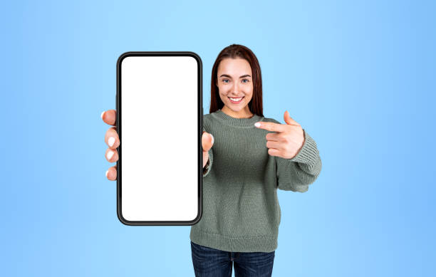 istock Woman pointing at phone mockup display on light background 1394731324
