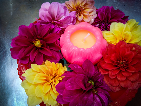 Penang, Malaysia. 

Flowers of various colours arranged in a circle surrounding a (lit and unlit) lotus candle. Gray background.