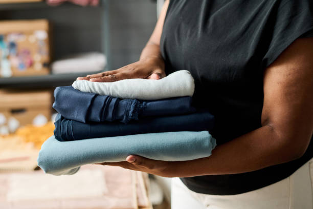istock Close-up of young African American tailor carrying stack of folded textile 1394736248