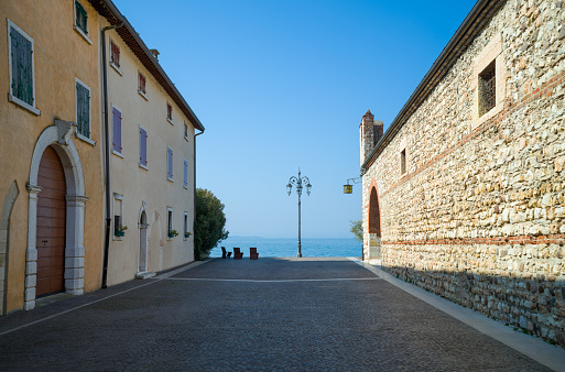 Italy, Lazise, a street leading to the lake shore with the old custom building on the right