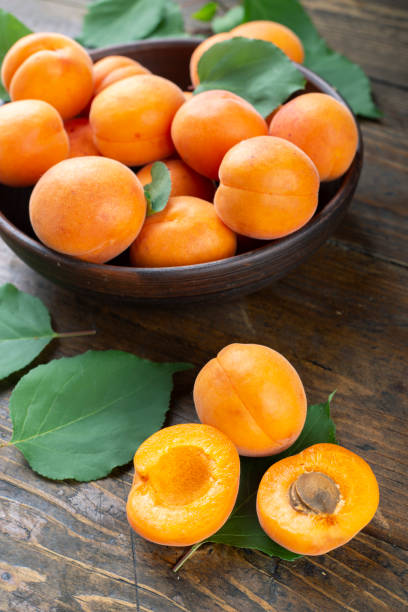 Delicious ripe apricots in a clay bowl on the table close-up. stock photo