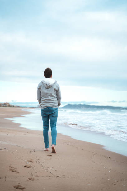 istock Lonely man walking on a foggy beach. depression concept. 1394738759