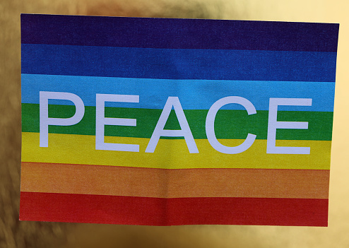 peace flag with the colors of the rainbow and the big text on the golden background symbol of war