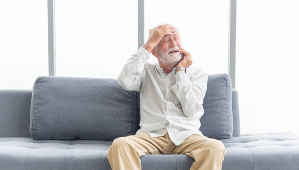 istock Elderly patients in sofa. Senior man patients headache hands on forehead. Man touching forehead suffering from severe headache or recalling bad memories. Medical and healthcare concept 1394739659