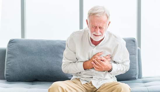 Senior male asian suffering from bad pain in his chest heart attack at home. Senior heart disease. Man with chest pain suffering from heart attack at home