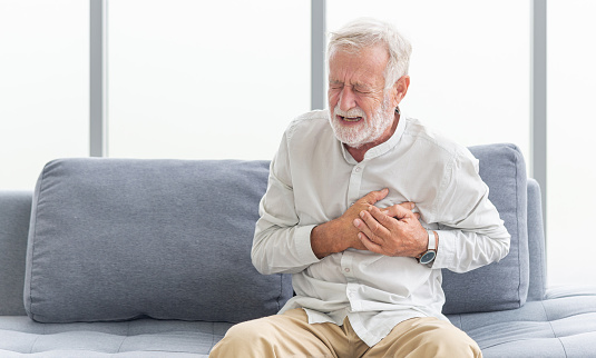 Senior male asian suffering from bad pain in his chest heart attack at home. Senior heart disease. Man with chest pain suffering from heart attack at home