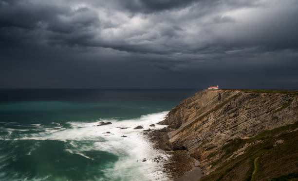 vista del faro en los acantilados de cabo vidio bajo un cielo nublado y tormentoso - cudillero fotos fotograf�ías e imágenes de stock