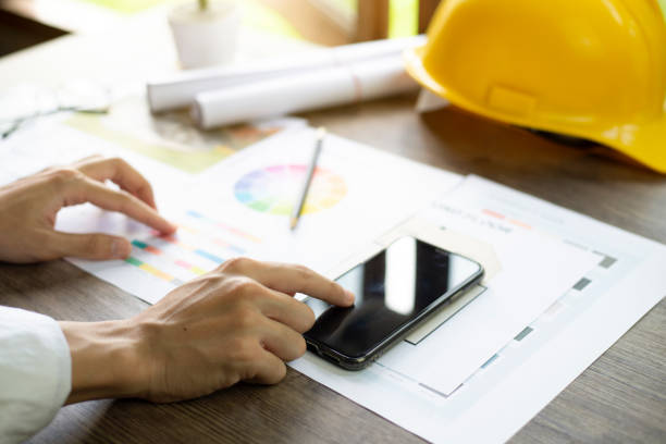 istock Architect's desk, Architects are comparing designs in smartphone, Close up at hand. 1394744310